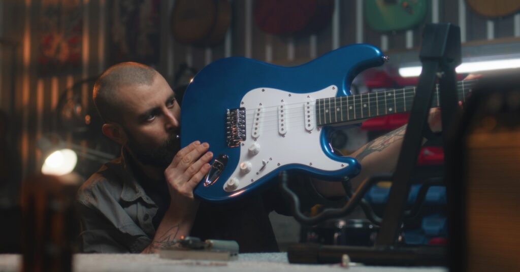 A guitar craftsman holding an electric Telecaster in his hands while eyeing it to make sure that it’s straight.